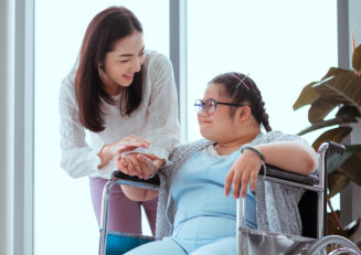 Caregiver monitoring woman with special needs as she paints