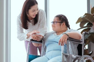 Caregiver monitoring woman with special needs as she paints