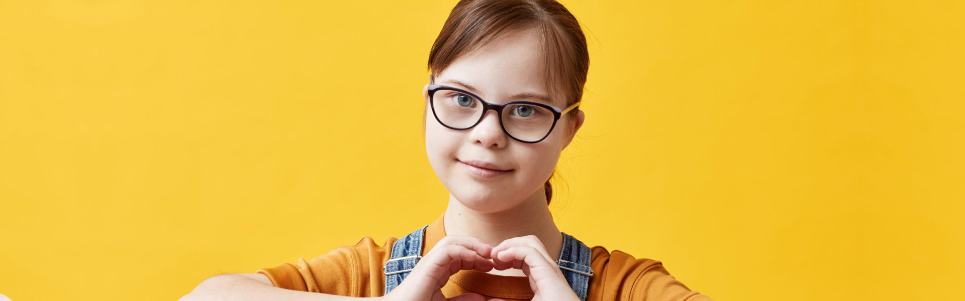 Girl with special needs forming a heart shape with her hands